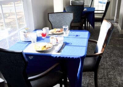 Bright dining room with blue tablecloths, plates of breakfast food, coffee, and juice at Charter Senior Living.