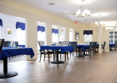 Spacious dining room at Charter Senior Living of Paris, TN with blue tablecloths, modern chairs, and bright natural lighting