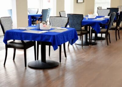 Bright dining room with blue tablecloths at Charter Senior Living of Paris in Paris, TN