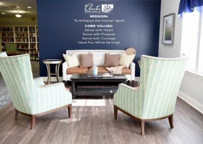 Seating area at Charter Senior Living of Paris with cozy armchairs, a sofa, and a mission and core values wall.