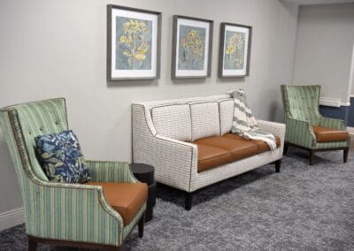 Cozy seating area with modern chairs, a patterned sofa, and floral artwork at Charter Senior Living of Paris, TN