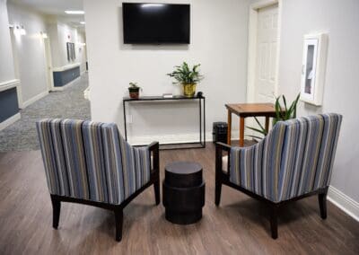 Cozy seating area at Charter Senior Living of Paris, TN, featuring two striped armchairs, a small black side table, and a wall-mounted flat-screen TV.