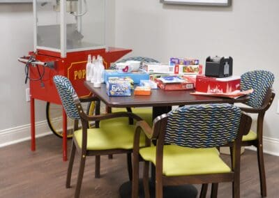 Table with board games and a popcorn machine in a vibrant community activity room at Charter Senior Living.