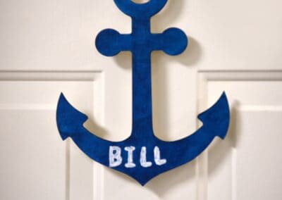 Blue anchor-shaped door decoration labeled 'Bill' hanging on a white door.