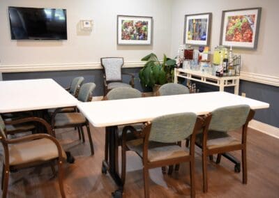 Activity room with tables, chairs, refreshment station, and wall art at Charter Senior Living of Paris, TN